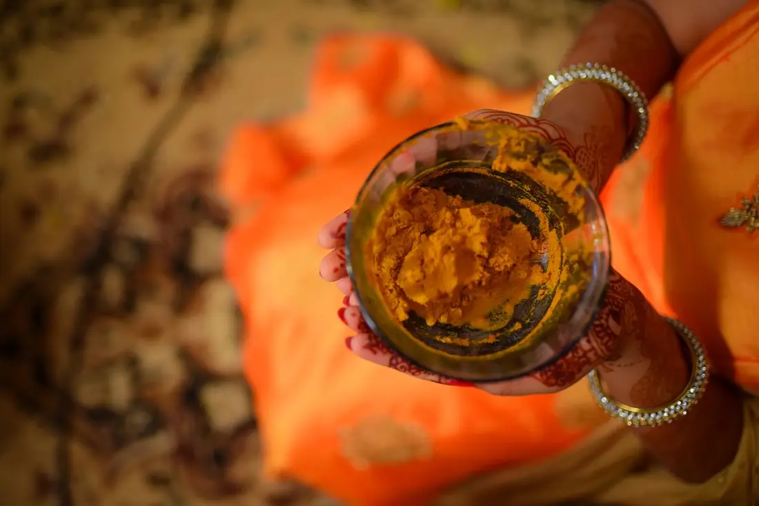 Hands applying turmeric during the haldi ceremony
